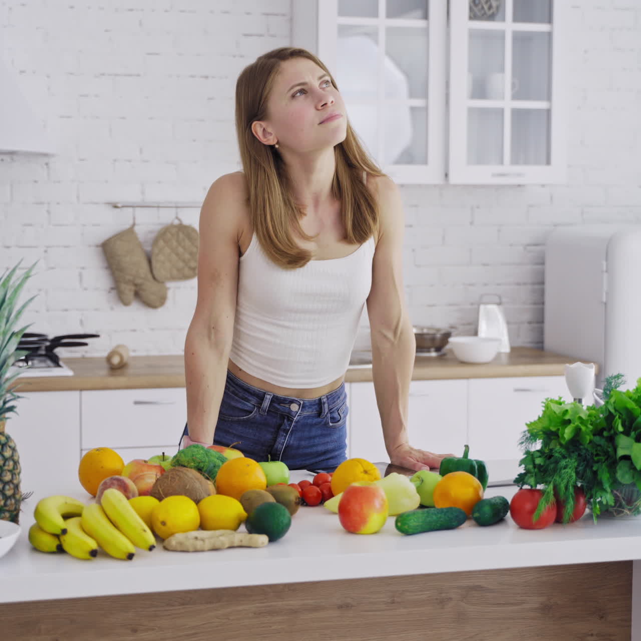 Young female with tablet in the kitchen. Attractive woman trying to find recipe for diet food in her laptop indoors. Healthy diet eating.