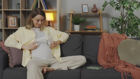 pregnant woman listening to music on the sofa
