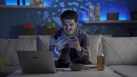joven viendo un video en el teléfono con asombro y bebiendo alcohol.