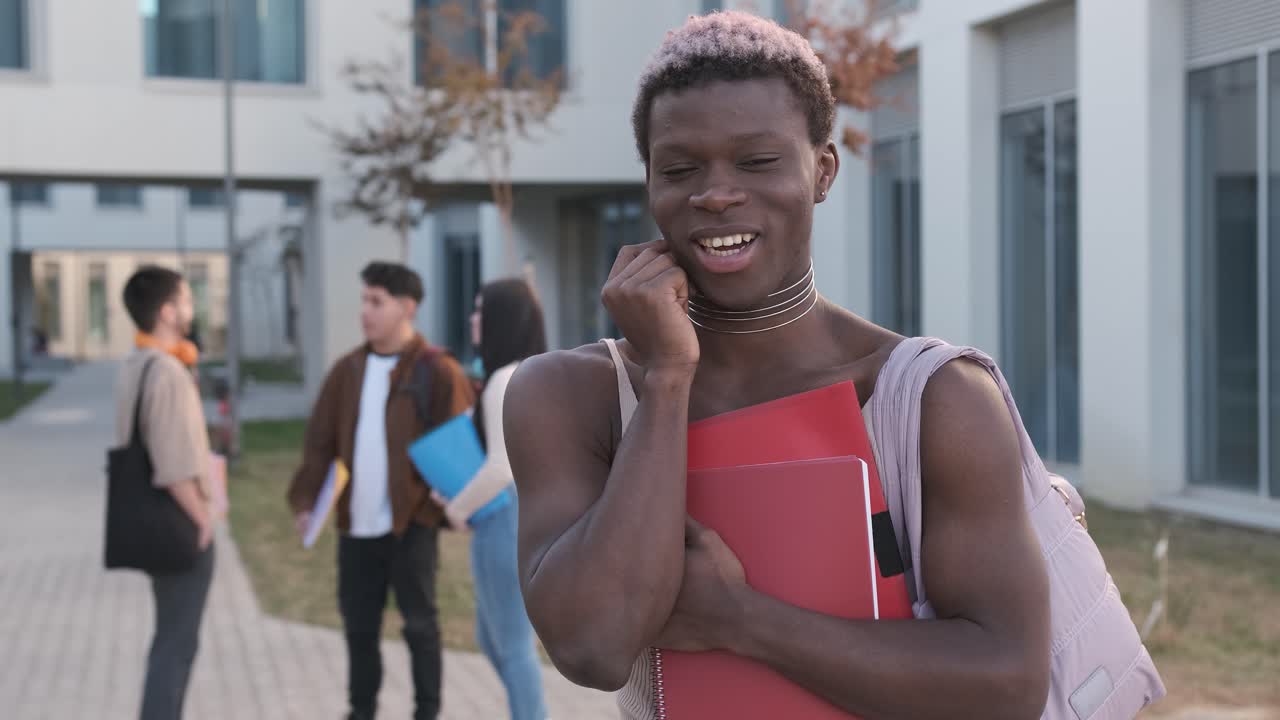 Transgender person smiling at the camera standing in a university campus