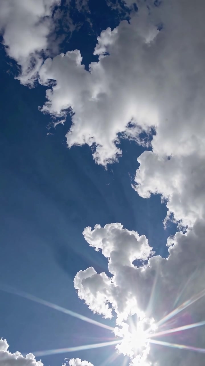Sunlight Beaming Through White Clouds in a Clear Blue Sky