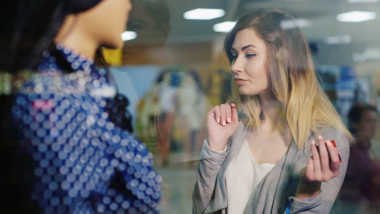 Young Attractive Woman Contemplates Showcase Clothing Store In The Hands In Her Card For Shopping An