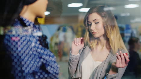 una mujer joven y atractiva contempla una tienda de ropa de escaparate en las manos de su tarjeta para comprar un