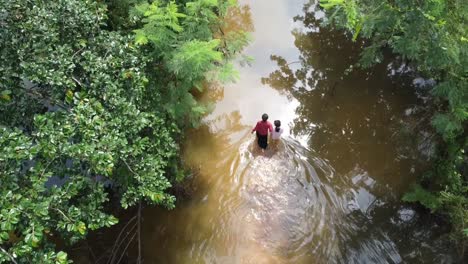 lonely family struggling through a flooded street caused by heavy rainfall in cambodia