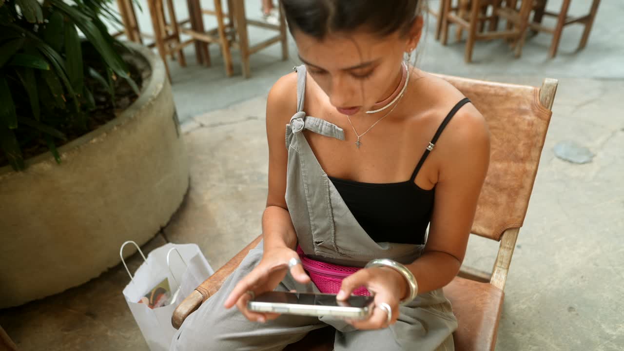 Woman using smartphone while sitting in chair indoors
