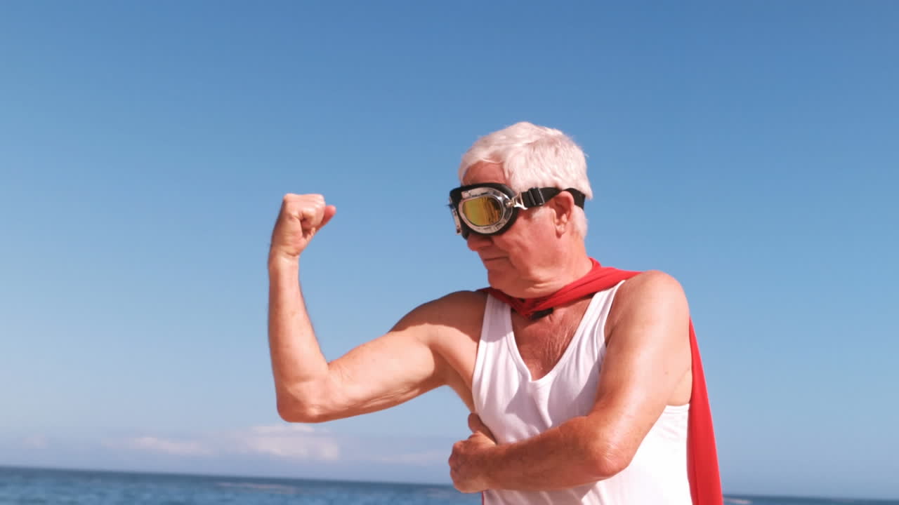 animación de hacerlo por ellos más feliz caucásico hombre mayor en disfraz de superhéroe en la playa