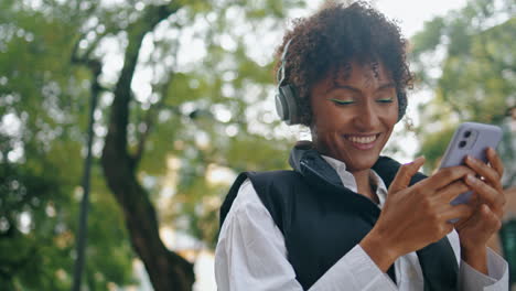 Woman-turning-on-music-at-wireless-earphones-standing-city-street-close-up.