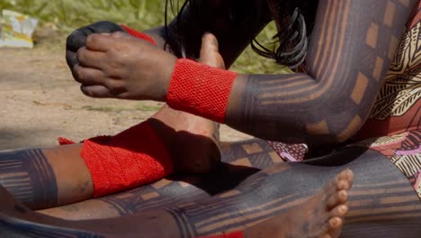 amazonian tribesperson hand-stitching orange cuffs, slow motion