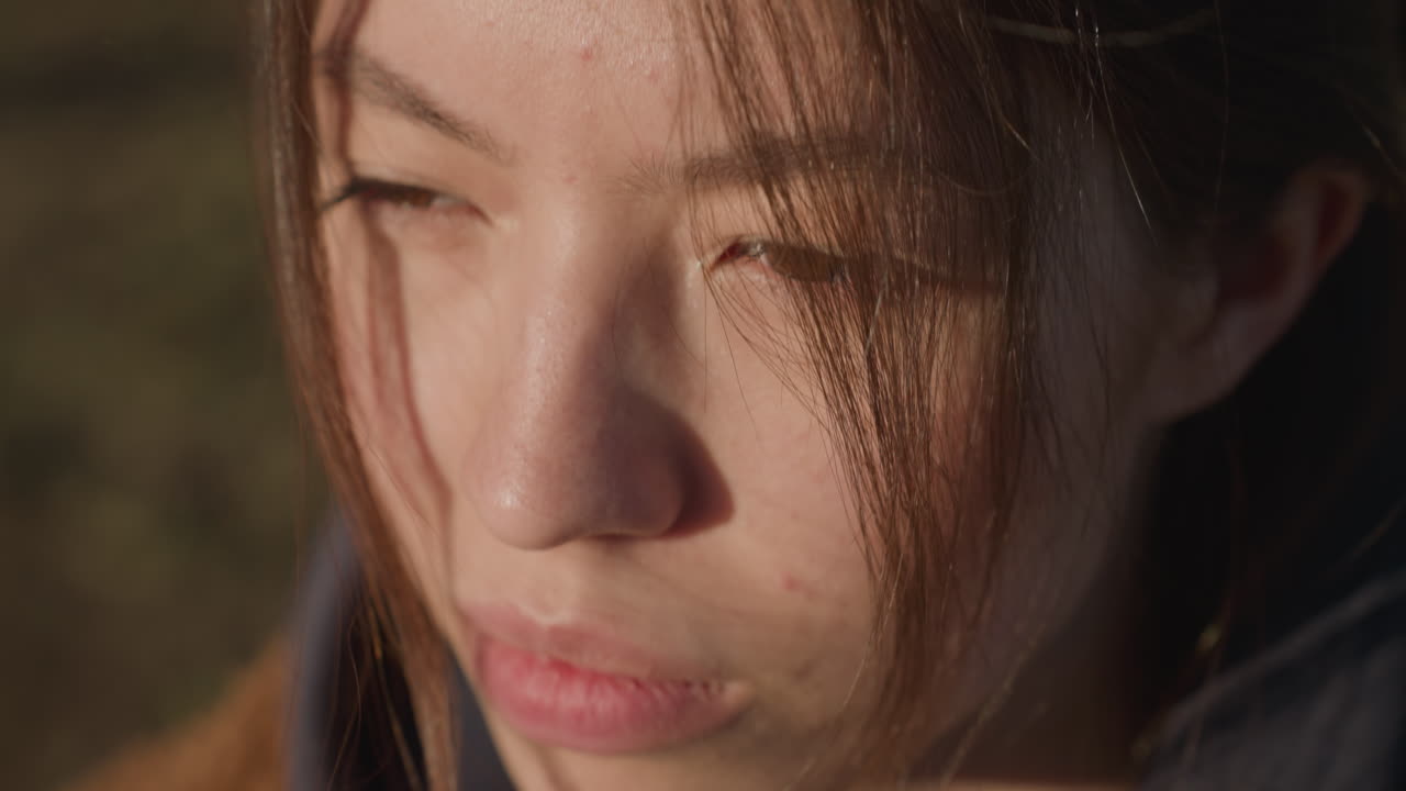 눈이 닫힌 소녀의 클로즈업, 그녀의 표정은 깊이 슬프고, 그녀의 머리카락은 부분적으로 그녀의 얼굴을 고, 우울함과 내성의 감각을 더합니다.