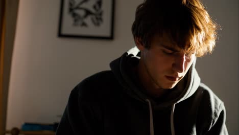 concentrating young man immersed in a book by the window, basking in natural light and enjoying a serene moment of leisure, personal growth, and quiet reflection indoors