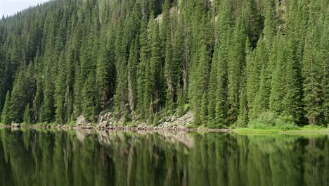 low aerial drone footage over a glassy beaver lake, in beaver creek, colorado