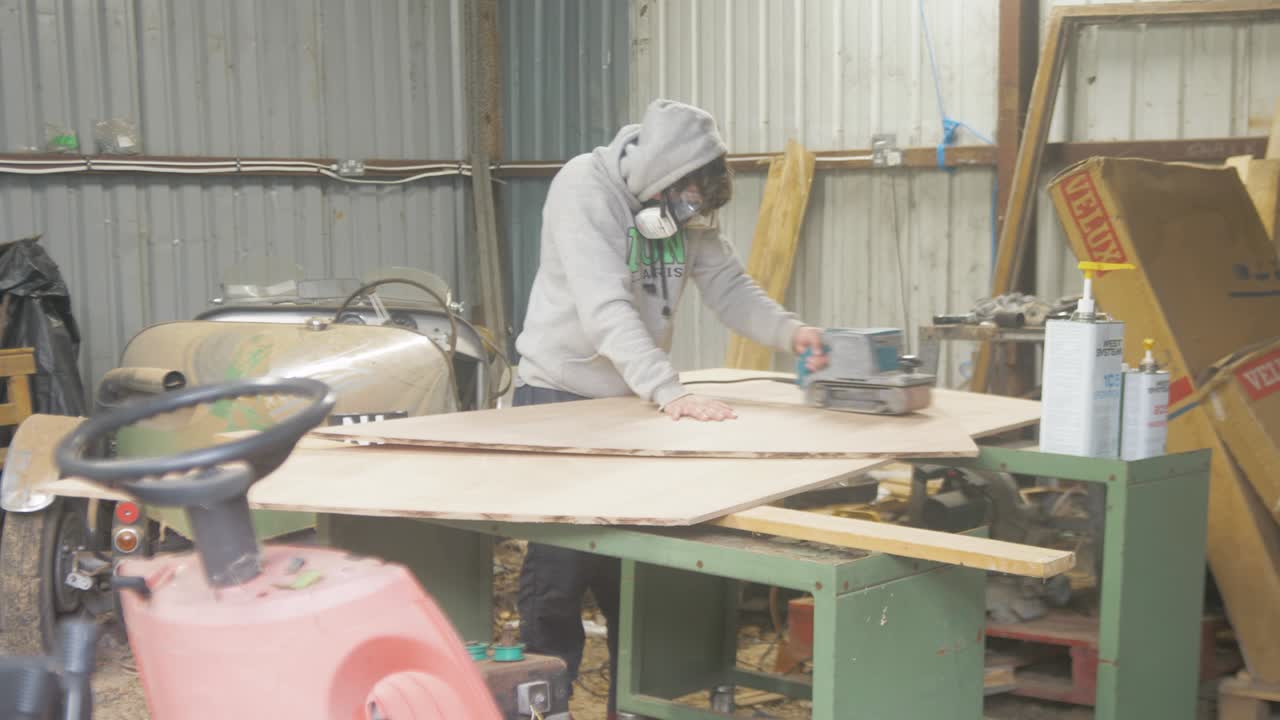 Man sanding plywood in a workshop