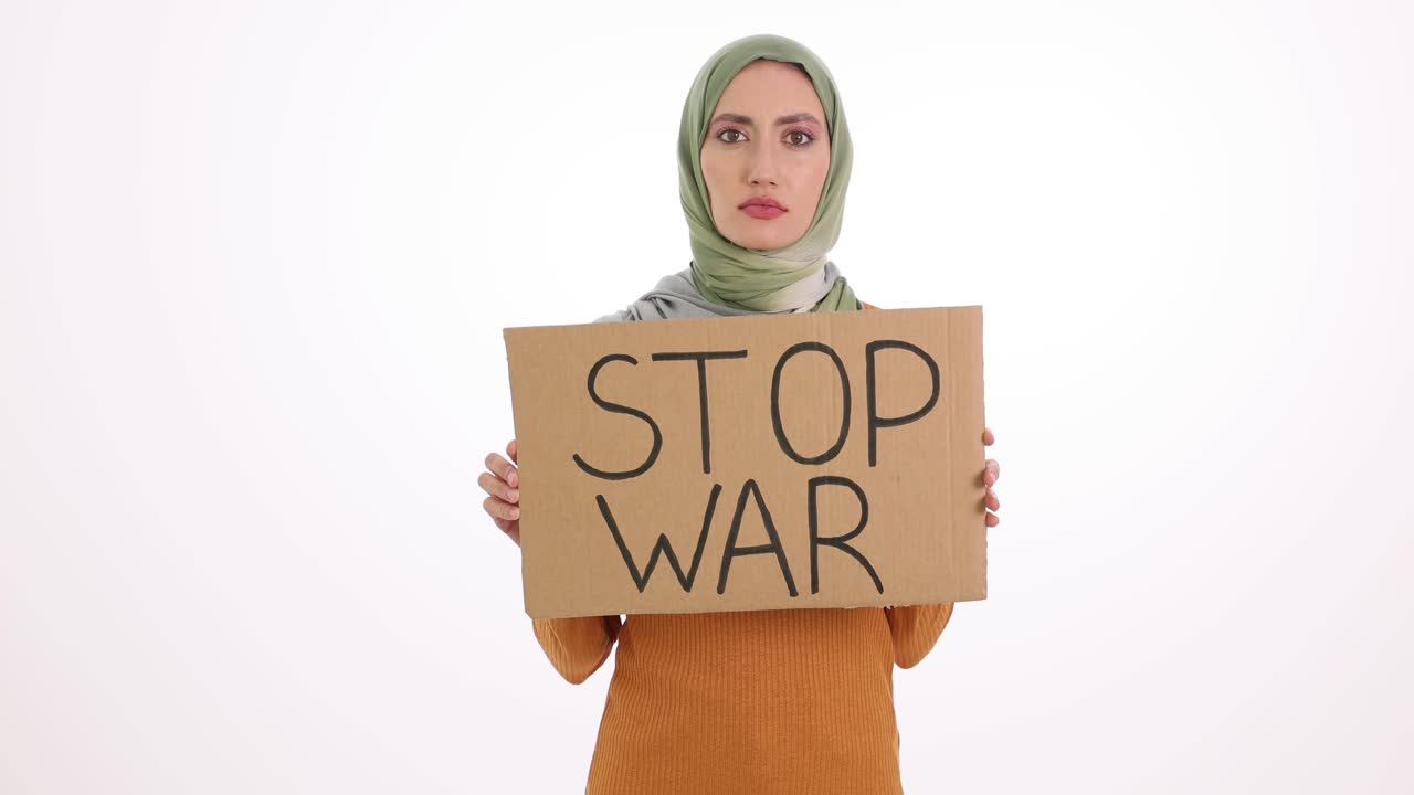 Donna con hijab che tiene un cartello "STOP ALLA GUERRA" su sfondo bianco