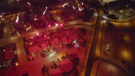 new year's eve fireworks display in snowy neighborhood at night in iceland. aerial orbiting shot