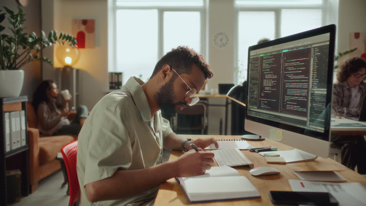 Programmer on Coding on Computer and Taking Notes at Office Workplace