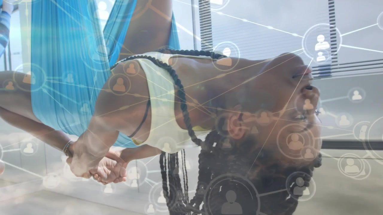 woman performing aerial yoga inversion in fitness studio, showing network icons overlay