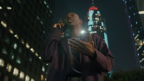 Young-happy-black-man-talking-on-the-phone-in-city-at-evening