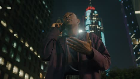joven negro feliz hablando por teléfono en la ciudad por la noche