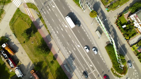 Aerial-circling-top-down-of-many-cars-driving-on-central-road-during-sunny-day-outdoors-in-nature