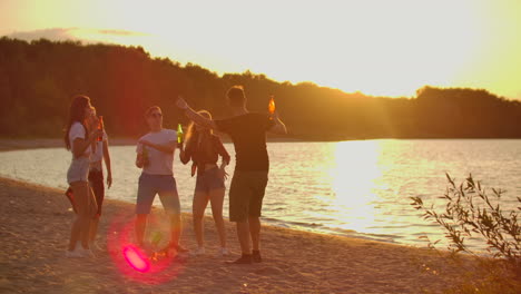 los cinco estudiantes celebran el final del año educativo en la fiesta al aire libre en la costa del lago con cerveza. es una fiesta de playa loca y caliente entre los mejores amigos alrededor de la hoguera.