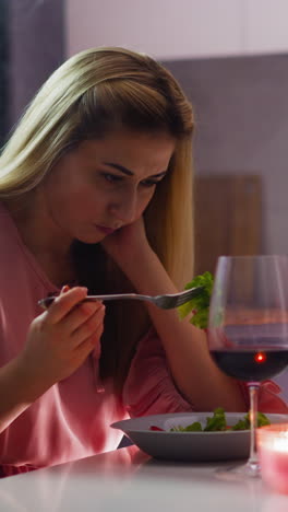 una mujer rubia triste con ropa elegante escoge la comida en el plato sufriendo de una cita romántica fallida en la mesa en la cocina en cámara lenta