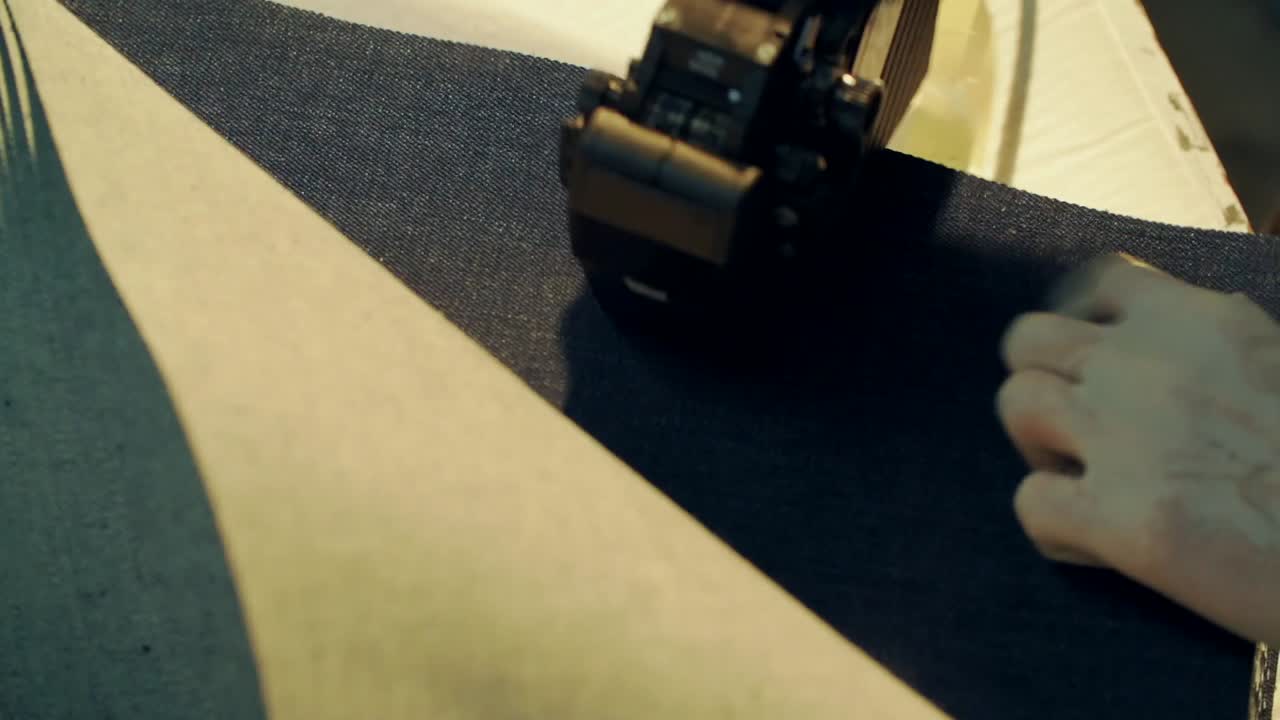 The man working in the jeans factory is numbering the denim fabrics