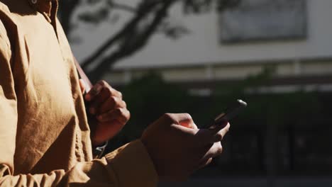 Midsection-of-african-american-businessman-using-smartphone-in-street