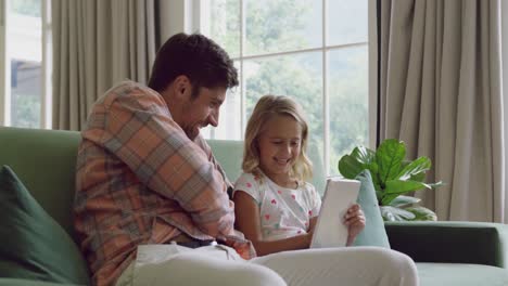 Father-and-daughter-using-digital-tablet-on-sofa-at-home-4k