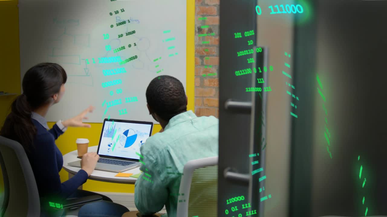Pair pointing at laptop and board, reviewing data charts while green code overlaying glass and team