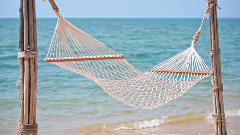 empty hammock on exotic beach with sea in background