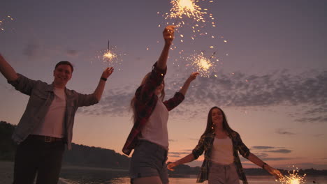 Group-of-friends-having-fun-running-on-the-beach-with-sparklers