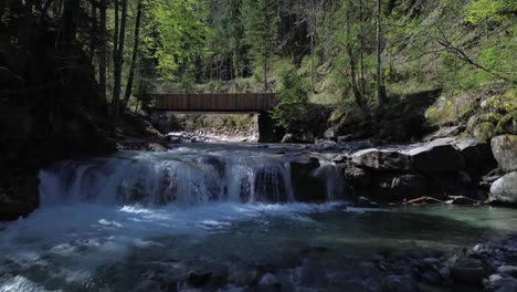 drone tilt up shot flight above beautiful mountain river towards bridge surrounded by forest