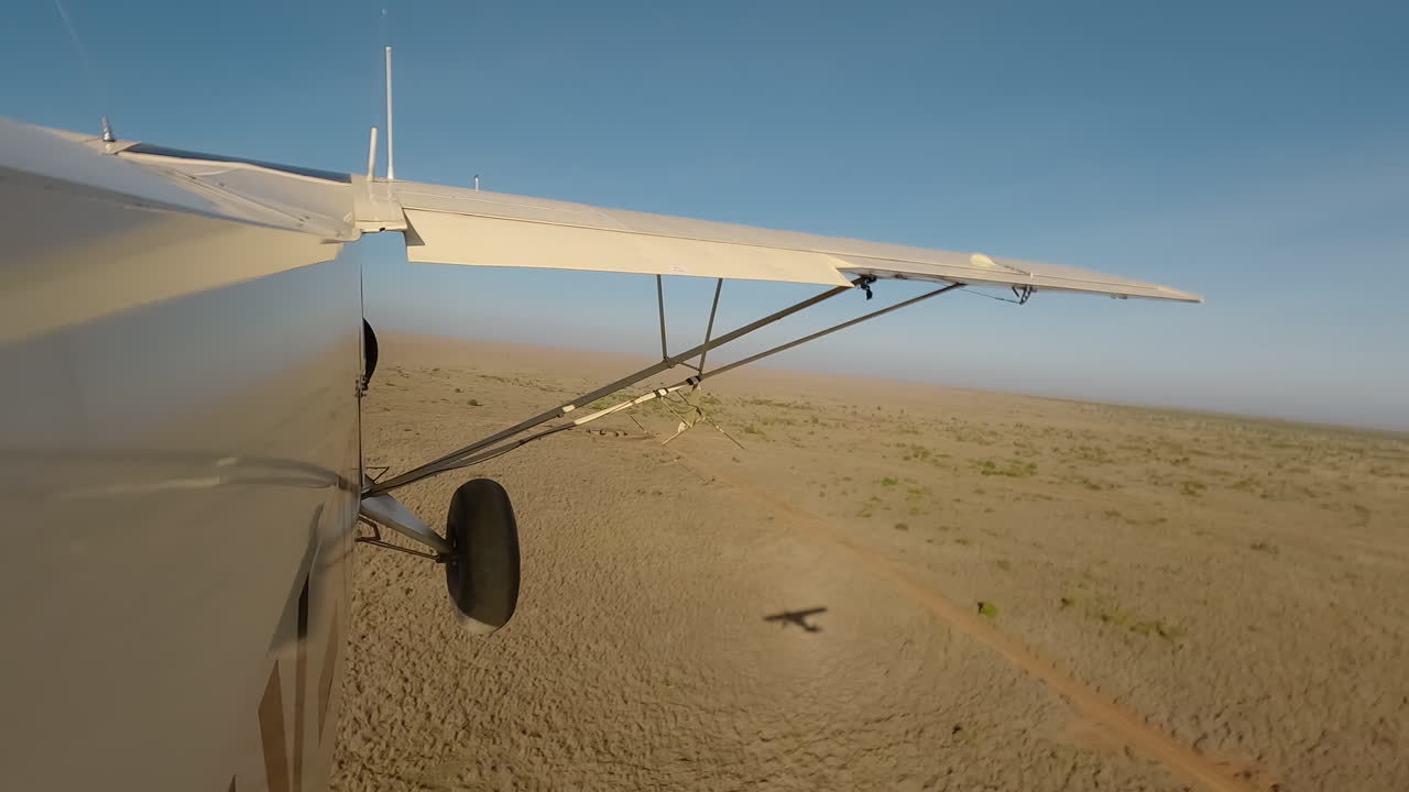 Vista laterale di un piccolo aereo che vola basso sopra gli arbusti di un podere.