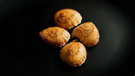 four shell-shaped coconut cookies on a black plate