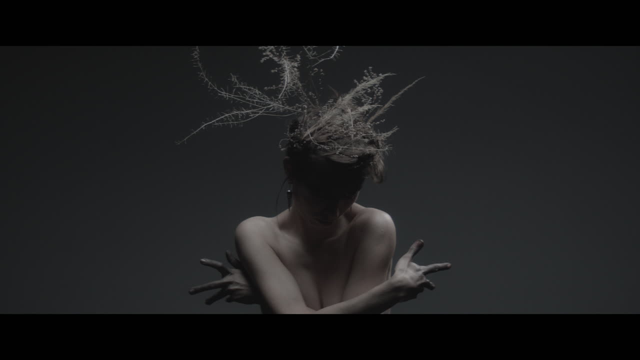 Uma mulher vestida como mãe natureza move-se lentamente em um movimento de dança
