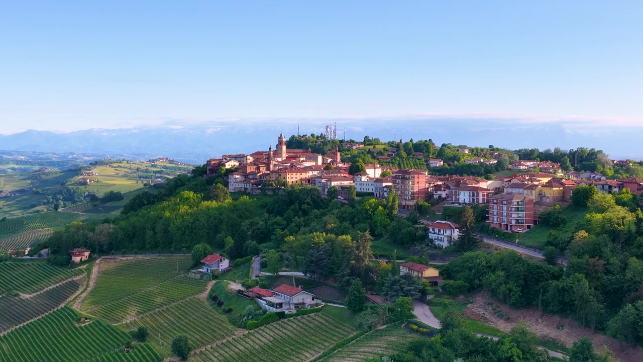 Riprese con drone catturano un villaggio storico in cima a una collina circondato da rigogliosi vigneti verdi e dolci colline.