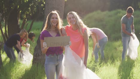 mid adult smiling and looking at camera with woman holding community sign during river clean-up day