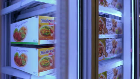 rows of frozen food in a supermarket display freezer
