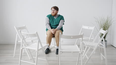 Man Sitting in a Circle of Chairs
