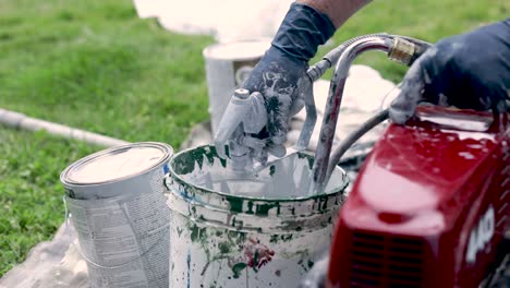 person cleaning the paint sprayer machine after using it