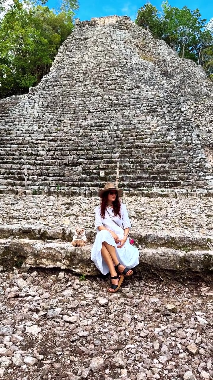 Turista presso un'antica piramide Maya. Donna che riposa sui gradini di pietra di un'antica piramide Maya circondata dalla giungla.