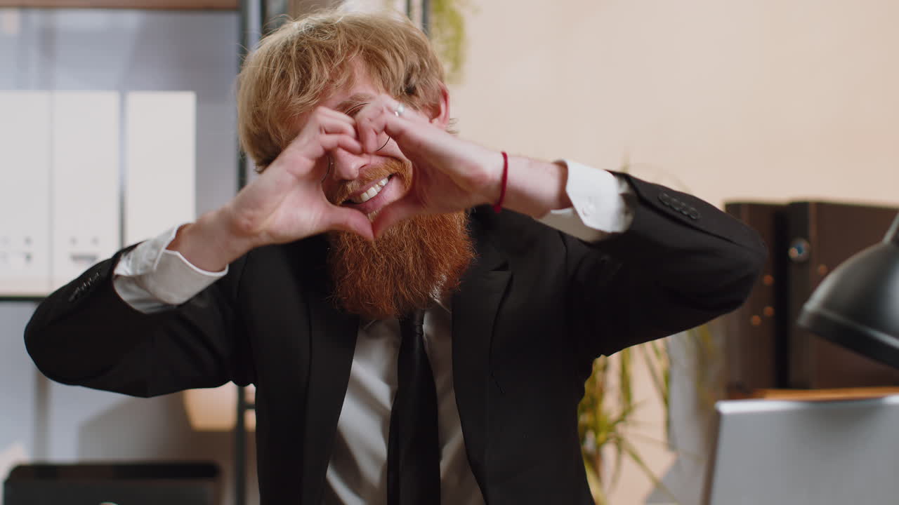 Young business man makes symbol of love showing heart sign to camera express romantic feelings