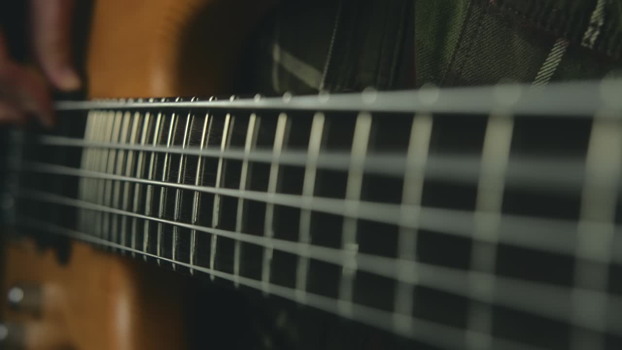 video de cerca de cuerdas de bajo en cámara lenta sobre fondo oscuro, hombre tocando la guitarra bajo