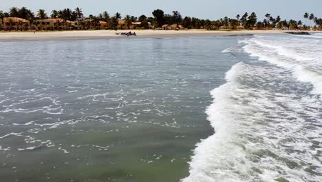 aerial drone fly low above sea waves of cape point bakau beach the gambia, africa, travel destination