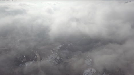 an aerial view of a snowy mountain pass while flying through hazy clouds
