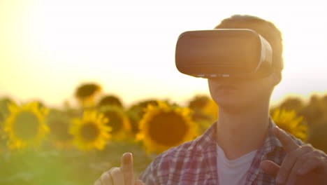 the concept of technological farming. the use of virtual reality in agriculture. a farmer at sunset uses gestures to control a farm and a field of sunflowers