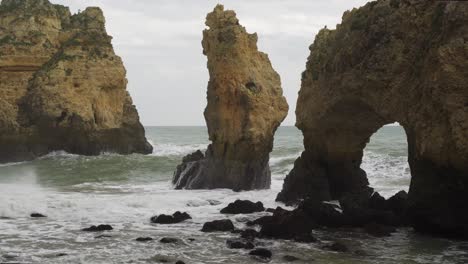 Große-Wellen-Schlagen-Gegen-Die-Felsen-Der-Küste-Und-Erodieren-Und-Bilden-Natürliche-Bögen-Und-Felsbrücken-An-Der-Ponta-Da-Piedade,-Algarve-In-Portugal