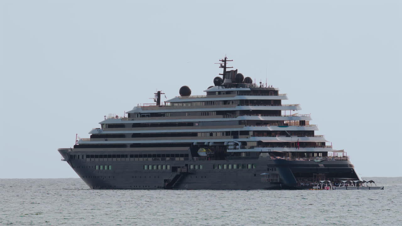 Massive luxury cruise ship sailing on calm sea under pale sky