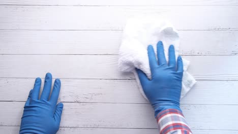 cleaning a wooden table with gloves