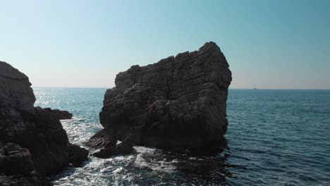 Disparo-De-Un-Dron-Bajo-Sobre-El-Agua-Entre-Rocas-Marinas-En-Un-Día-Soleado